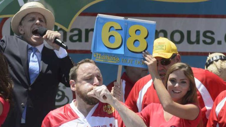 Joey Chestnut, center, competes against Matt Stonie, left, and other competitive eaters during Nathan's Famous Fourth of July International Hot Dog Eating Contest in Coney Island, Brooklyn, on Monday, July 4, 2016. Chestnut won after consuming 70 hot dogs.