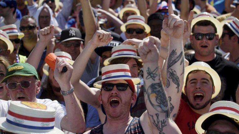 Fans cheer as they wait for the start of Nathan's Famous Fourth of July International Hot Dog Eating Contest in Coney Island, Brooklyn, on Monday, July 4, 2016. This year marks the 100th anniversary of the annual Fourth of July hot dog eating contest.