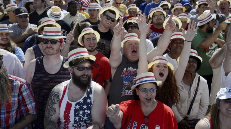 Fans cheer as they wait for the start of Nathan's Famous Fourth of July International Hot Dog Eating Contest in Coney Island, Brooklyn, on Monday, July 4, 2016. This year marks the 100th anniversary of the annual Fourth of July hot dog eating contest.