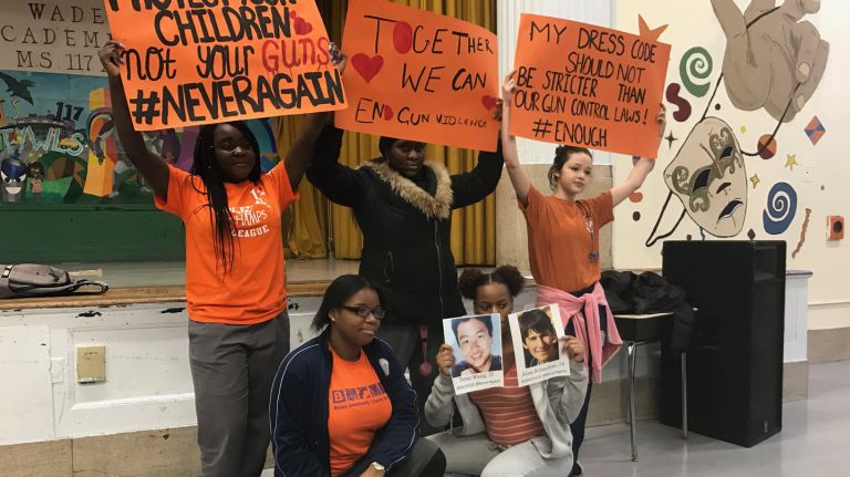 Taniya Evanson, 15, and Mercedes Clarke, 16, kneeling, joined classmates , from left, Eileen Twisami, 15,  Mikayla Sumter Malone, 16, and Madison Abreu, 16, in organizing the walkout at the Young Women's Leadership School of the Bronx on Wednesday. They held posters made by the school's art department before  walking out with other  students.