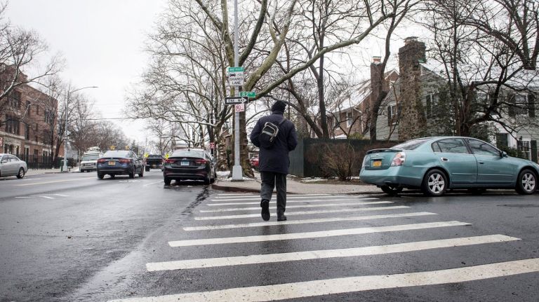 A man crosses the street at the intersection of 82nd and Kew Gardens roads in Queens where a woman was fatally hit by a mini school bus Tuesday,  March 13, 2018. 