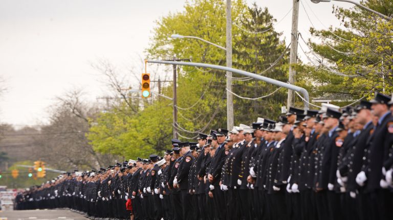 Firefighters salute as the funeral procession for FDNY firefighter William Tolley passes the Bethpage Volunteer Fire Department on Long Island, Thursday, April 27, 2017.
