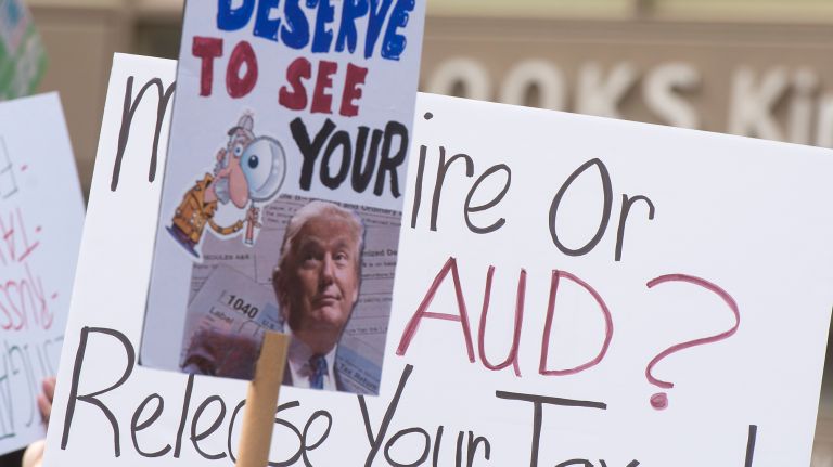 Protesters hold signs calling on President Donald Trump to release his tax returns during a march in Bryant Park on Saturday, April 15, 2017.