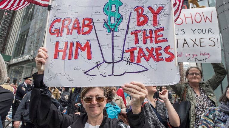 Abby Stokes holds her protest sign as she supported marchers going down Sixth Avenue on Saturday, April 15, 2017.