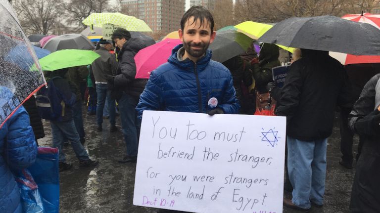 A man holds a sign that reads, 