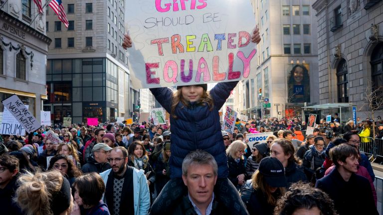 Owen Hughes of Brooklyn holds his daughter, Amali Hughes, 8, on his shoulders as they join other people marching in Manhattan on Saturday, Jan. 21, 2017, in solidarity with the Women's March on Washington during President Donald Trump's first full day in office.