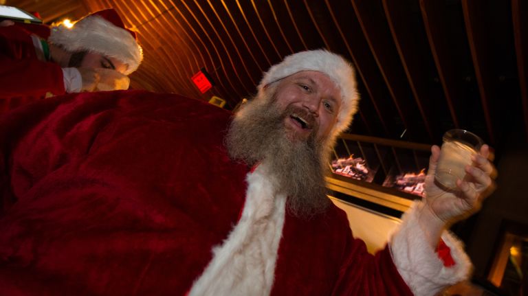 A man raises a glass during a SantaCon celebration at Ainsworth Park, a bar on East 18th Street in Manhattan, on Saturday, Dec. 10, 2016.
