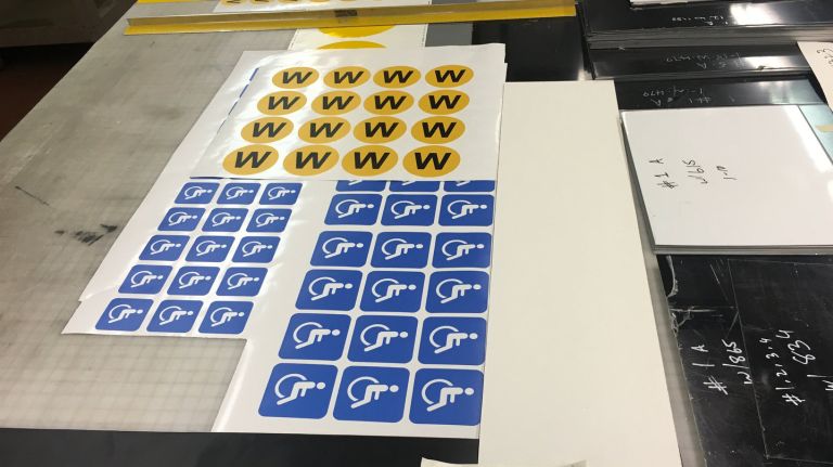 A sign fabricator's desk is covered in subway bullets and transfer paper. 