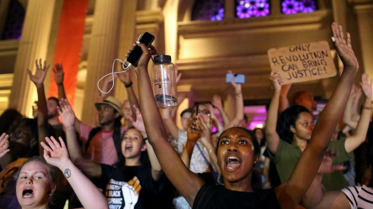 Demonstrators raise their arms with a chant of 