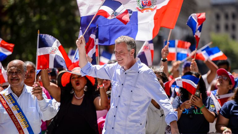 Mayor Bill de Blasio waves a flag as he marches in the Dominican Day Parade on Avenue of the Americas on Sunday, Aug. 13, 2017. 