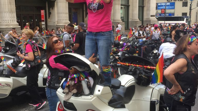 Patty Briand, of Lake Hopatcong, N.J., snaps photos while Elisa Aragon, of Kearny, N.J., helps keep her steady as the two wait for the start of the NYC Pride March on Fifth Avenue in Manhattan on Sunday, June 25, 2017.