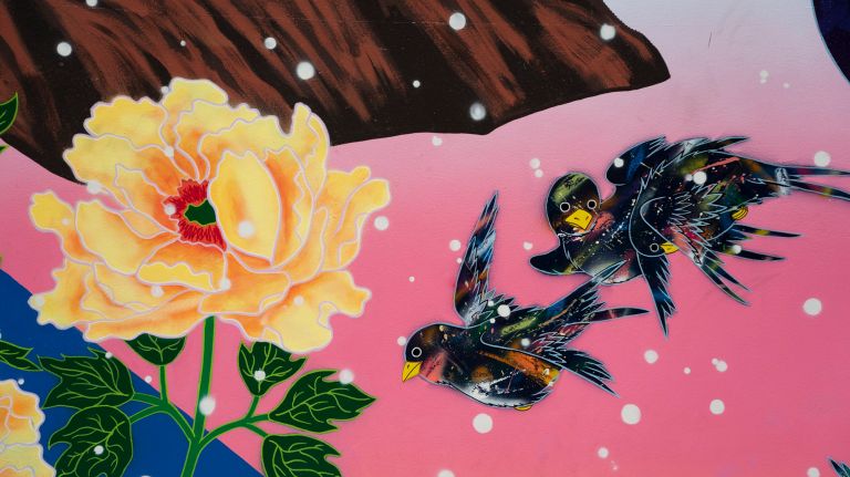 The mural features floral and winged imagery.