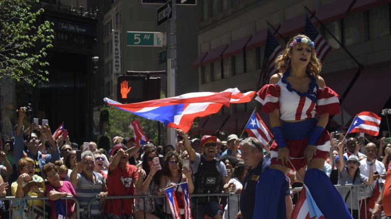 A woman on stilts entertains the crowd as she marches in the 59th annual Puerto Rican Day Parade in Manhattan on Sunday, June 12, 2016. 
