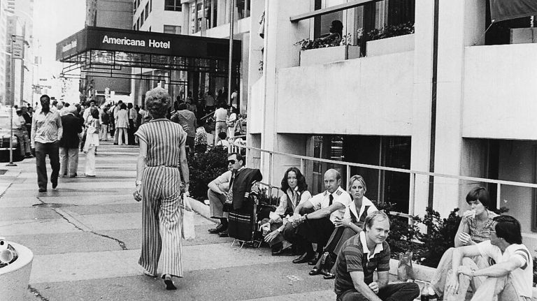 Hotel guests sit outside trying to keep cool in the shade of a building, which was a lot cooler than unairconditioned rooms during the blackout on July 14, 1977.