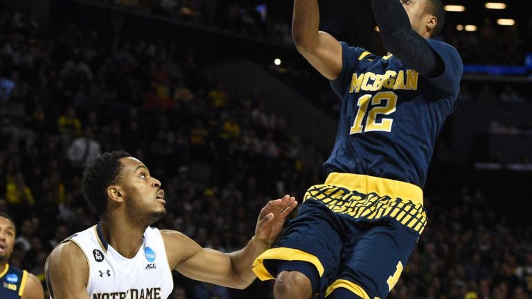 NCAA Tournament: Notre Dame vs. Michigan 18 Michigan Wolverines guard Muhammad-Ali Abdur-Rahkman scores a basket on a layup as Notre Dame Fighting Irish forward V.J. Beachem defends during the first round of an East Regional men's basketball game in the NCAA Tournament at Barclays Center on Friday, March 18, 2016.