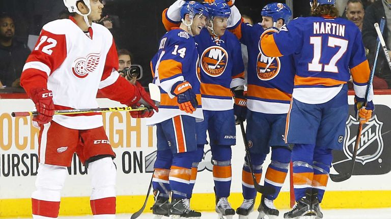 Andreas Athanasiou #72 of the Detroit Red Wings looks on as Marek Zidlicky #28 of the New York Islanders celebrates his second period goal with his teammates at Barclays Center on Monday, Feb. 15, 2016 in Brooklyn, New York.