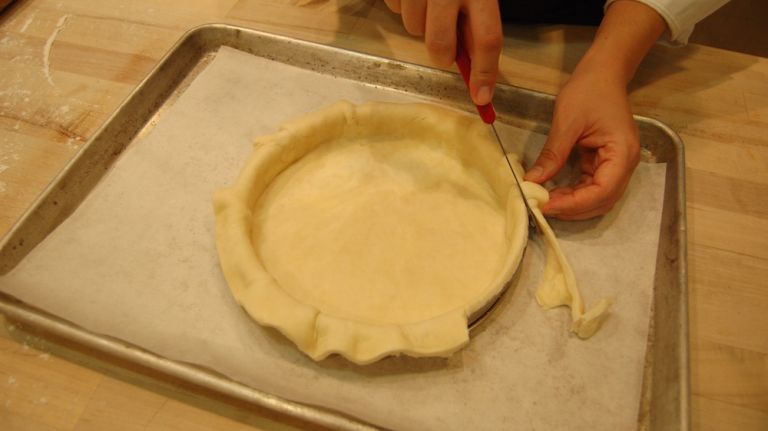 Cut the edge of the dough at an angle so it doesn't shrink into the ring or pie dish. A tiny bit of dough hanging over is ok. 