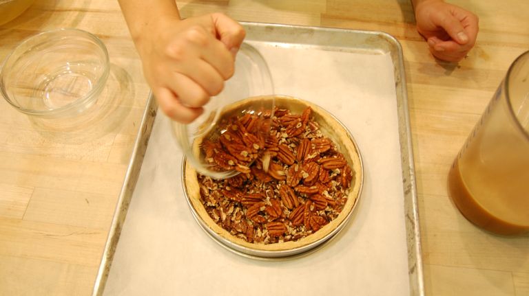 Remove the shell from the oven. (If using ring, leave it.) First scatter pecan pieces into shell, followed by pecan halves. You want the whole pecans on top.