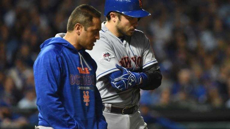 New York Mets trainer Ray Ramirez looks at New York Mets catcher Travis d'Arnaud (7) after he is hit by a pitch in the seventh inning during Game 4 of the NLCS against the Chicago Cubs at Wrigley Field on Wednesday, Oct. 21, 2015.