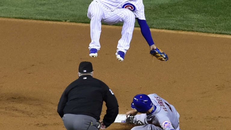 New York Mets shortstop Wilmer Flores (4) steals secondnd base as Chicago Cubs second baseman Javier Baez (9) comes down on his head in the first inning during Game 4 of the NLCS against the Chicago Cubs at Wrigley Field on Wednesday, Oct. 21, 2015.