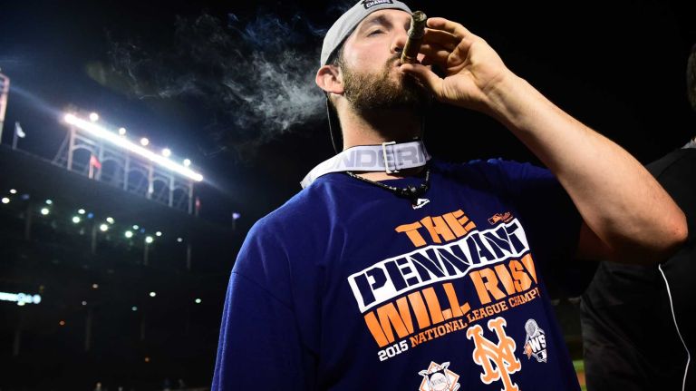 New York Mets Jonathan Niese smokes a cigar as he celebrates his victory in Game 4 of the NLCS against the Chicago Cubs at Wrigley Field on Wednesday, Oct. 21, 2015.