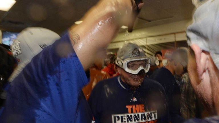 New York Mets pitching coach Dan Warthen (59) gets on bottle of champagne on his head as they celebrate with teammates as the New York Mets celebrate in the locker room the NLCS series win against the Chicago Cubs at Wrigley Field on Wednesday, Oct. 21, 2015.