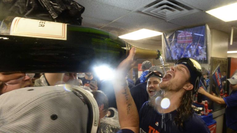 New York Mets starting pitcher Jonathon Niese (49) pours a big bottle of champagne into Mets starting pitcher Jacob deGrom's mouth as teammates celebrate in the clubhouse after beating the Chicago Cubs in the NLCS at Wrigley Field on Wednesday, Oct. 21, 2015.
