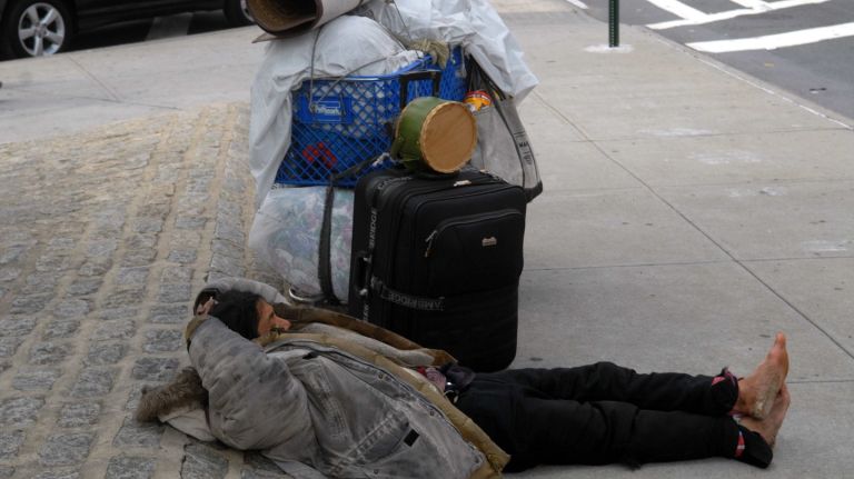 A person sleeping on a New York City sidewalk.
