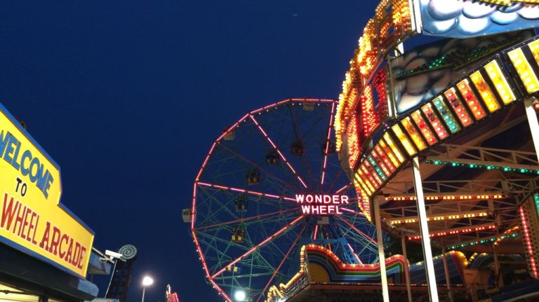 The classic neon Wonder Wheel signs hangs over the lights of the amusement park on July 18, 2015. 