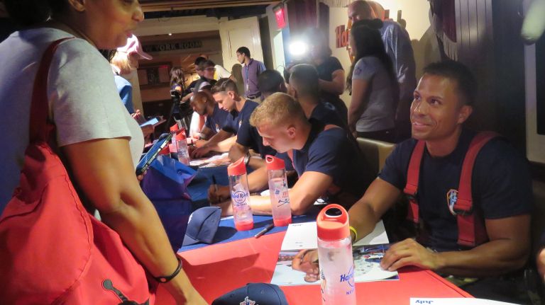 Firefighters signing fans' 2016 FDNY calendars. 