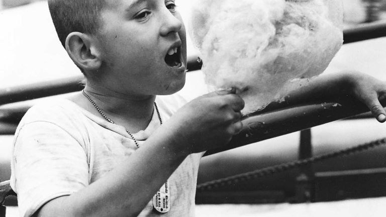 Opening day at Rockaways' Playland finds Robert Lester, 9, of Lynbrook, enjoying a giant batch of cotton candy while waiting for his turn on the ride. (May 24, 1952)