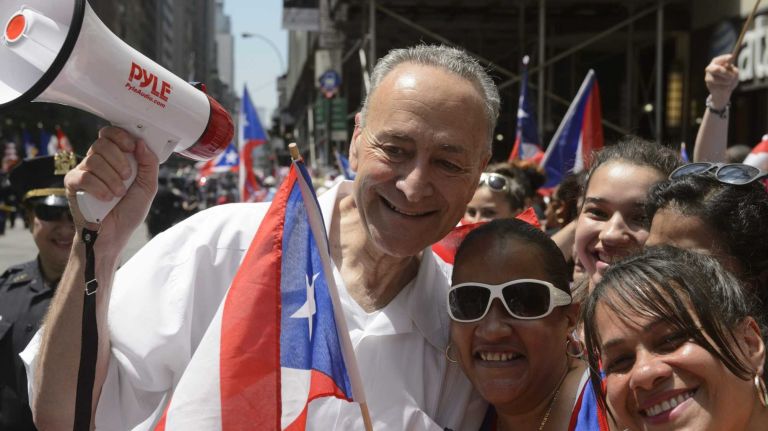 U.S. Senator Charles E. Schumer, left, stops for a photograph as he marches along 5th Avenue during the 58th annual Puerto Rican Day Parade in Manhattan on June 14, 2015. The annual parade celebrates Puerto Rican heritage and culture. It is one of the largest parades in New York City.