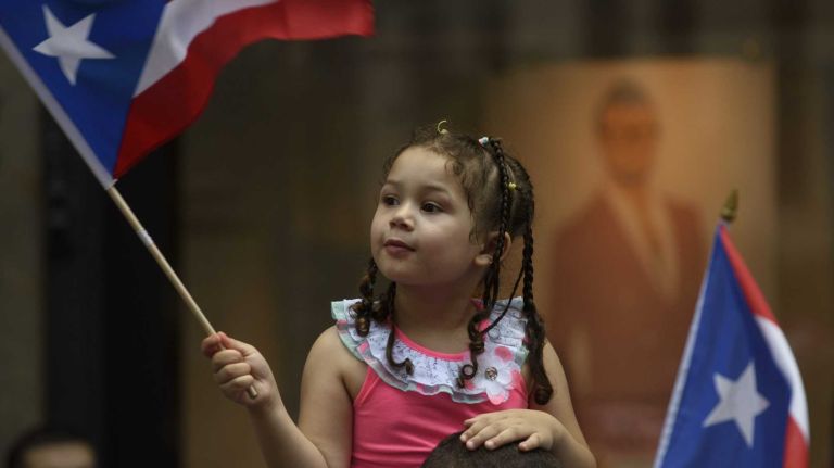 Kiomara Martinez, of San Juan, Puerto Rico, waves her flag as she watches the 58th annual Puerto Rican Day Parade in Manhattan on June 14, 2015. The annual parade celebrates Puerto Rican heritage and culture. It is one of the largest parades in New York City.