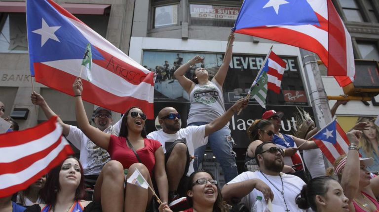 Spectators wave flags as they line 5th Avenue during the 58th annual Puerto Rican Day Parade in Manhattan on June 14, 2015. The annual parade celebrates Puerto Rican heritage and culture. It is one of the largest parades in New York City.