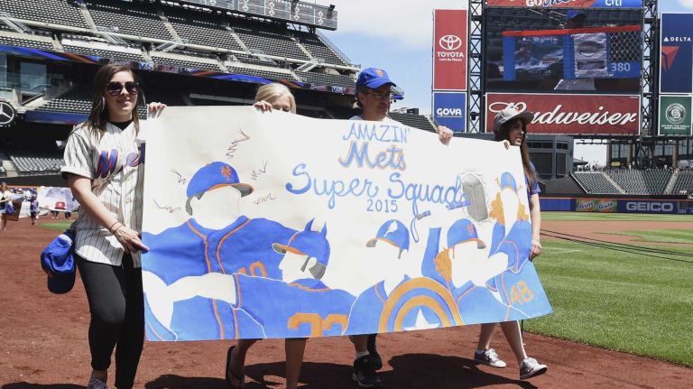 New York Mets fans walk with banners along the warning track at Citi Field on Banner Day before a baseball game between the Mets and the Atlanta Braves on Sunday, June 14, 2015.