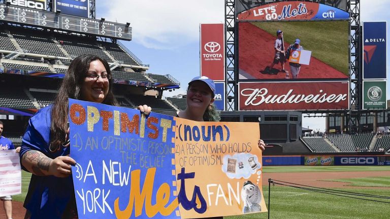 New York Mets fans walk with banners along the warning track at Citi Field on Banner Day before a baseball game between the Mets and the Atlanta Braves on Sunday, June 14, 2015.
