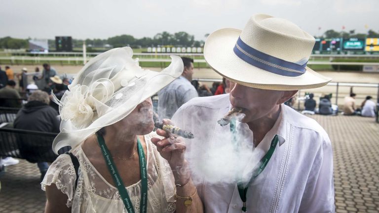 Loriann Reinhard of Middle Village, Queens, and Jeff Jensen of Connecticut enjoy a cigar hours before the race where Triple Crown challenger American Pharoah was looking to make history at Belmont Park Race Track in Elmont Saturday, June 6, 2015.