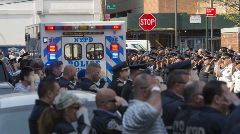 Officers salute as an ambulance carrying deceased NYPD Officer Brian Moore leaves Jamaica Hospital in Queens on Monday, May 4, 2015.