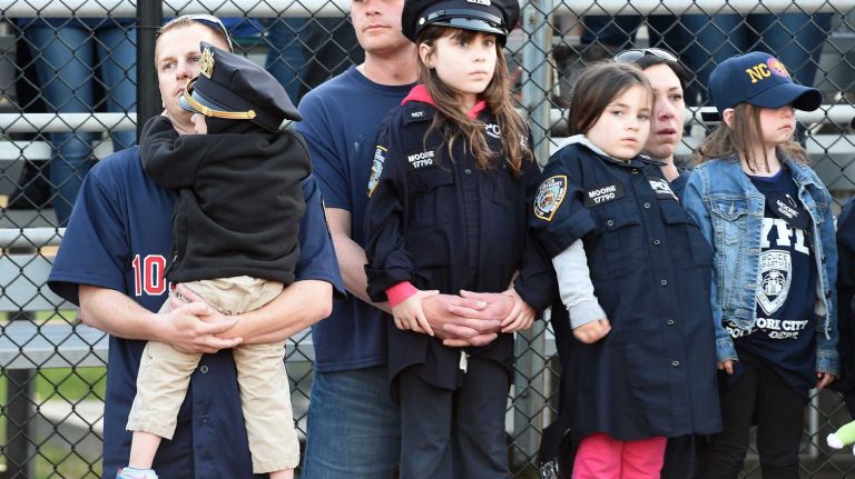 Family and friends of slain NYPD Police Officer Brian Moore gather at a memorial service for him on the football field of Plainedge High School, his alma mater, on Monday, May 4, 2015.