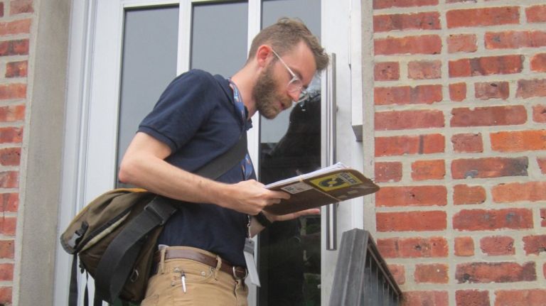 Sam Chaney, a city rent freeze specialist, presses a buzzer at a Flatbush building.
