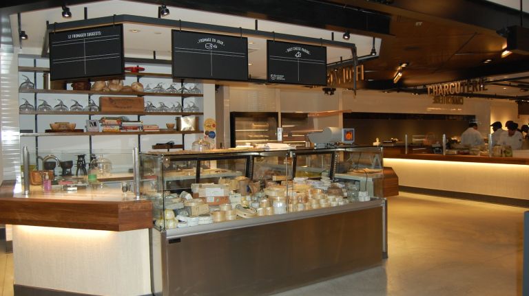 French food market Le District now open at Brookfield Place 15 This area of Le District features a fromagerie, boulangerie, rotisserie, bouchierie and poissonnerie, as well as a gorgeous bar in the middle of the room. Guests can pick up cuts of meat, D'Artagnan chicken or fish to take home, or can have it cooked on site and delivered to them while they enjoy a glass of wine at the bar. Have a post-work drink, pick up a steak for dinner and then stop into the Garden District...