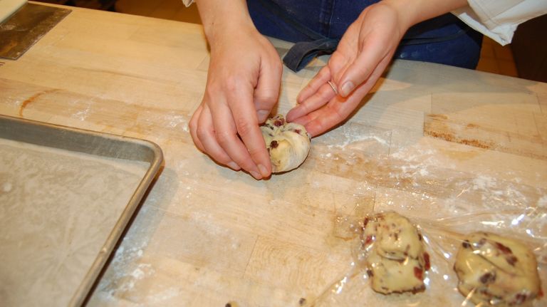 Cup your fingers around a portion of dough and, using the palm of your hand, press it down a bit to flatten slightly. Then, fold each side in to the middle, like you're sealing an envelope. There are about 4-5 sides of each portion. 