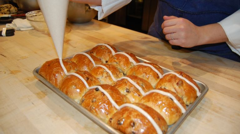 Starting at the left side of the top corner bun, pipe a continuous strip of icing across the center of the first row of 3 buns. Repeat with the remaining 3 rows. Then repeat in the opposite direction, across the 3 rows of 4 buns, working in the opposite direction, to create a cross of frosting on each bun. 