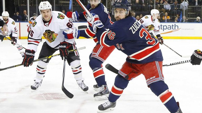 Mats Zuccarello of the New York Rangers keeps his eye on the puck in the first period as teammate Derick Brassard defends against Andrew Shaw of the Chicago Blackhawks at Madison Square Garden on Wednesday, March 18, 2015.