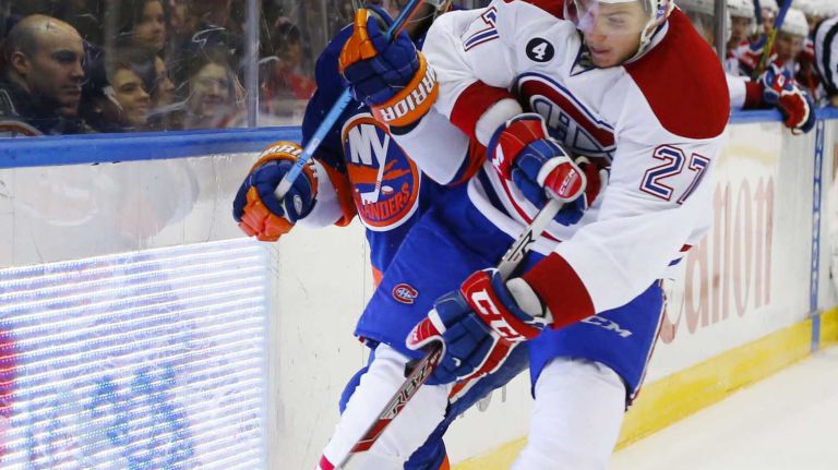 Alex Galchenyuk of the Montreal Canadiens battles Brian Strait of the New York Islanders for the puck in the second period at Nassau Coliseum on Saturday, March 14, 2015 in Uniondale.
