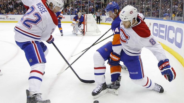 Brandon Prust and Dale Weise of the Montreal Canadiens battle for the puck in the second period against Calvin de Haan of the New York Islanders at Nassau Coliseum on Saturday, March 14, 2015 in Uniondale.