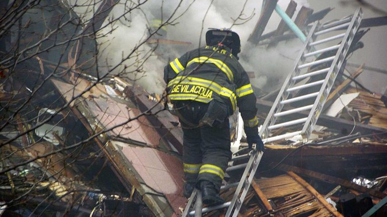 A fireman searches for survivors at a building explosion Wednesday, March 12, 2014, at 116th Street and Park Avenue in Manhattan.