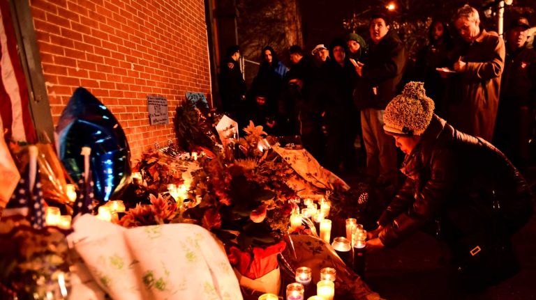 Candles and flowers are left at a makeshift memorial in Bedford-Stuyvesant on Sunday, Dec. 21, 2014, for NYPD Officers Rafael Ramos and Wenjian Liu, who were fatally shot near the intersection of Myrtle and Tompkins avenues a day before.