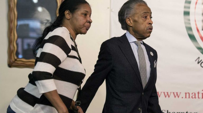 The Rev. Al Sharpton walks with Esaw Garner, wife of Eric Garner, before he and the family members of Garner denounced violence in their loved one's name Sunday, Dec. 21, 2014, at the National Action Network headquarters in Harlem, in the wake or the shooting deaths of NYPD officers Wenjian Liu and Rafael Ramos.