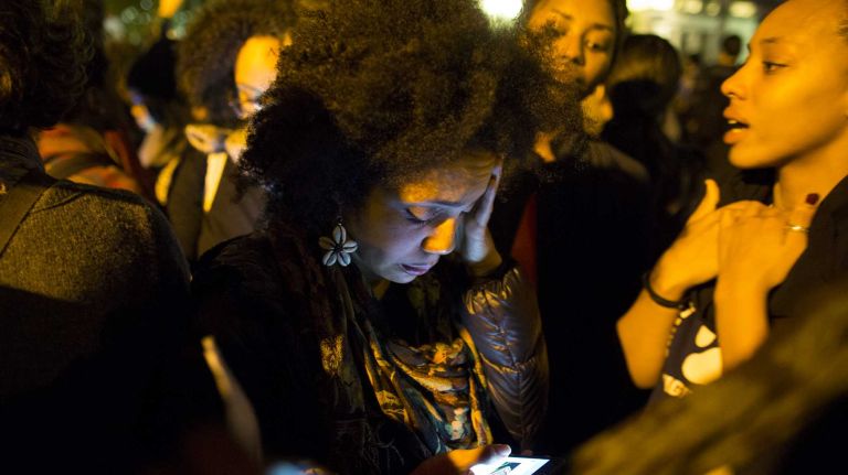 A protester reacts quietly while reading from a smartphone in Union Square Monday, Nov. 24, 2014, just after the grand jury decision was announced in Ferguson, Mo.